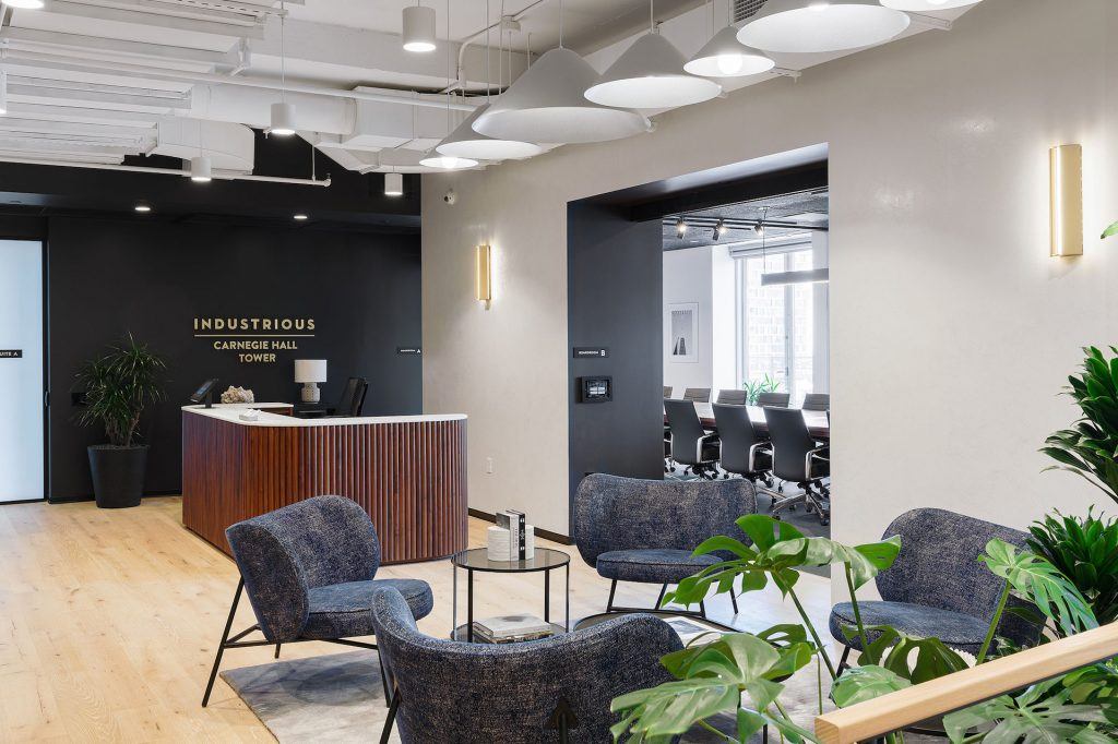 Oak wood flooring and ample greenery create an inviting reception area in Industrious Carnegie Hall Tower.
